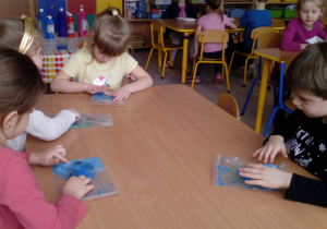 Dzieci siedzące przy stoliku podczas zabawy sensorycznej.